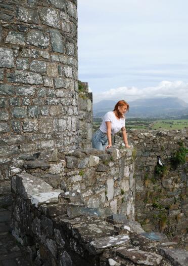 A young person looking over the wall in an old castle ground