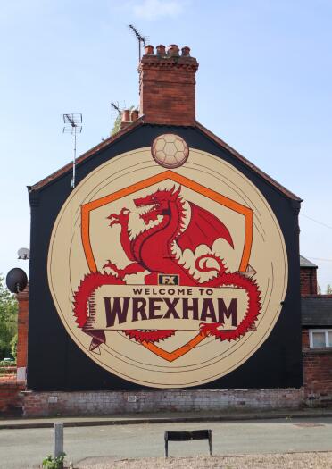 Large painted mural on the side of a house that reads "Welcome to Wrexham" over a red dragon