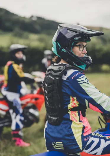 ヘルメットとバイクの安全具を着用し、バイクを抱え微笑む人