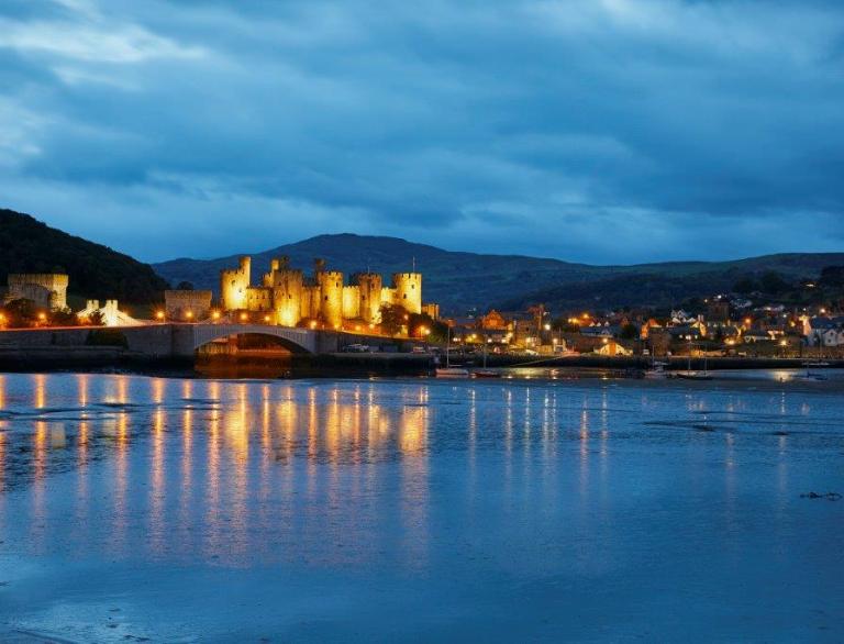 castle lit up at night with reflection on water