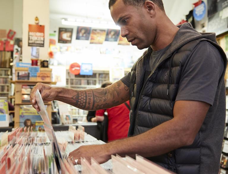 Un homme regarde des vinyles dans un magasin de disques.