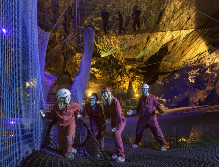 Visitantes en las camas elásticas subterráneos en rebote debajo de Blaenau Ffestiniog, país de Gales del norte