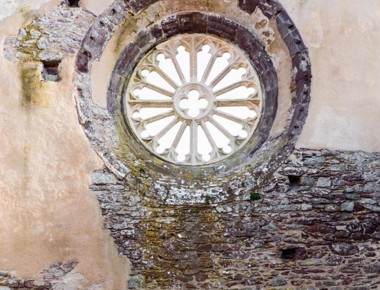 Alte Ruine mit rundem Fenster und Tür.
