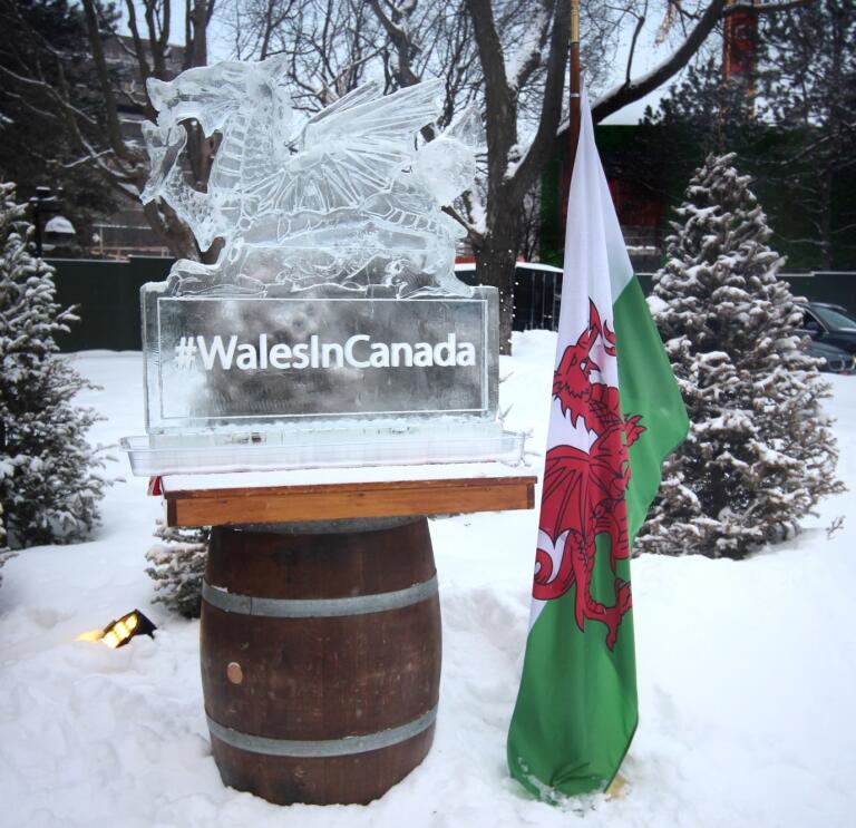 Photograph of an ice sculpture in the shape of the Welsh dragon, next to a Welsh flag