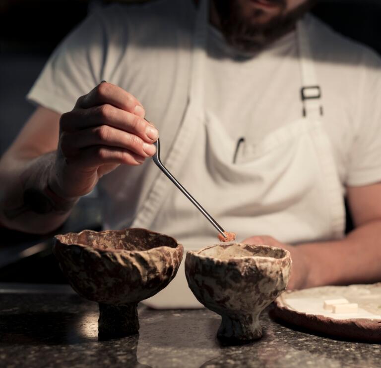 A chef preparing two bowls of food on a marble surface