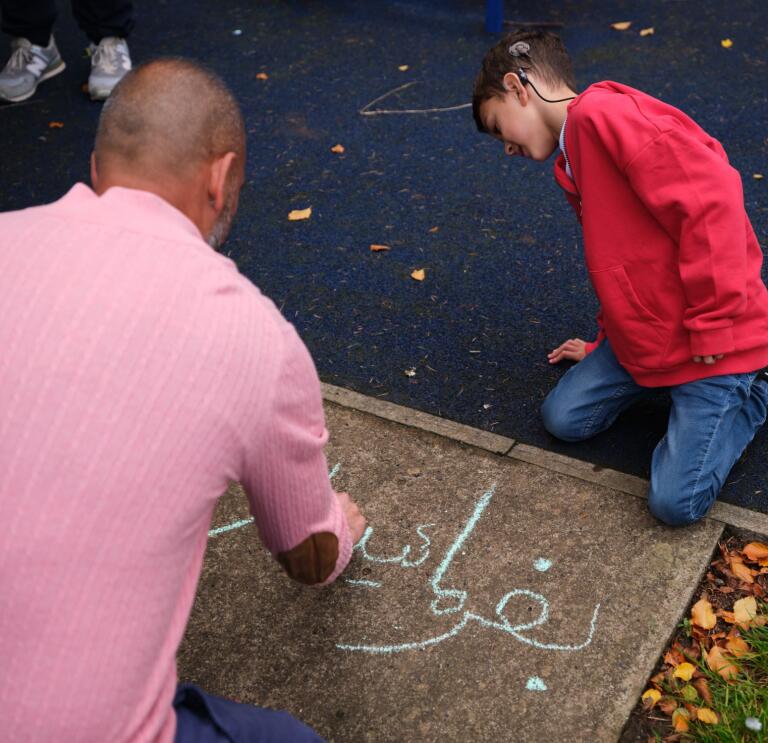 A man and his son drawing in chalk on the pavement