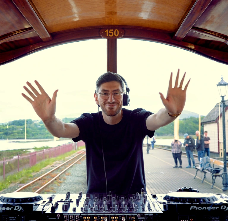 A man DJing at the back of a train.