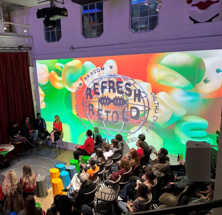 A large group of people in a room watching a panel discussion