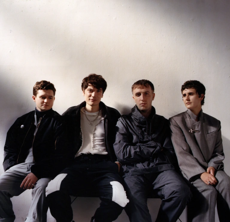 Four men sat down staring at the camera.
