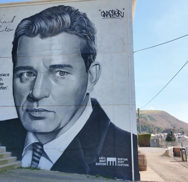 A large painting of Richard Burton on a wall.
