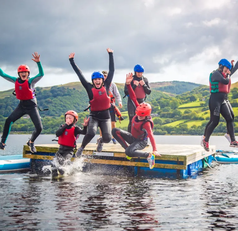 Children jumping off a float in the water.