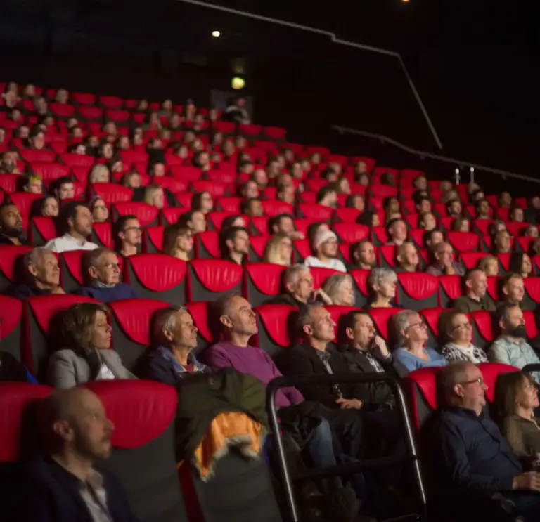 An audience in a large cinema watches a screening at the Iris Prize Festival.