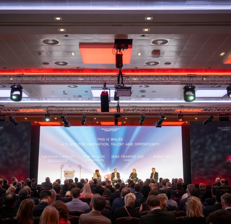 A panel of business people and professionals sitting on a stage in front of a large audience