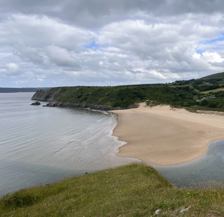 A scenic shot of a beautiful sandy bay with green mountains lining the sea