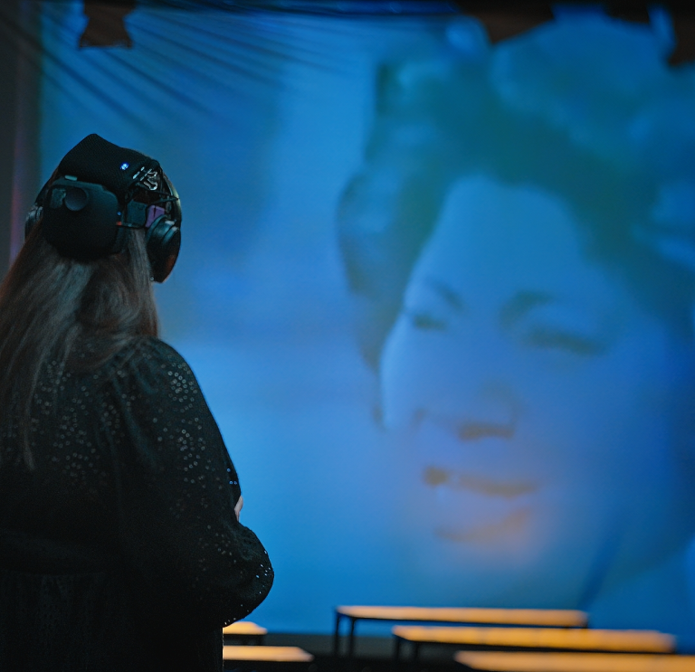 A person wearing headphones watching a show on screen
