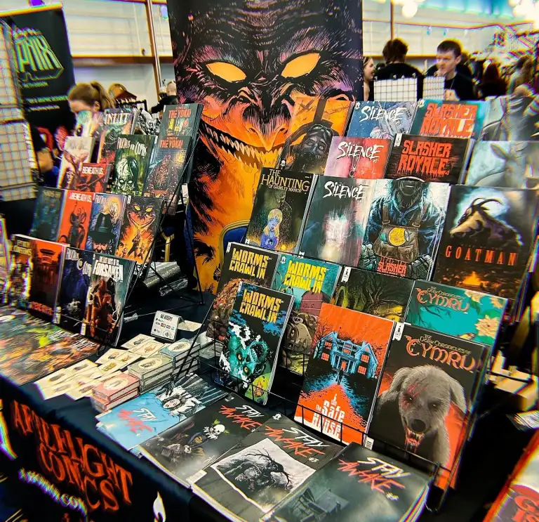A comic convention stall displaying horror comics and graphic novels by Joseph Oliveira of Afterlight Comics.