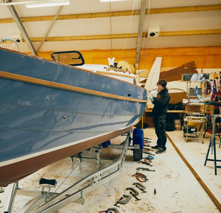 Handwerker bei Schwalbenjachten, die auf einem Boot in der Werkstatt arbeiten