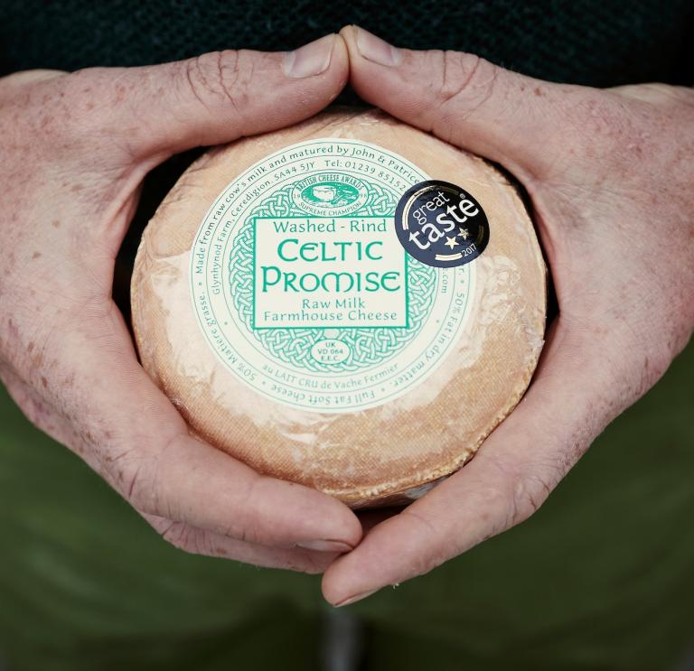 Primer plano de manos sosteniendo queso celta promesa.