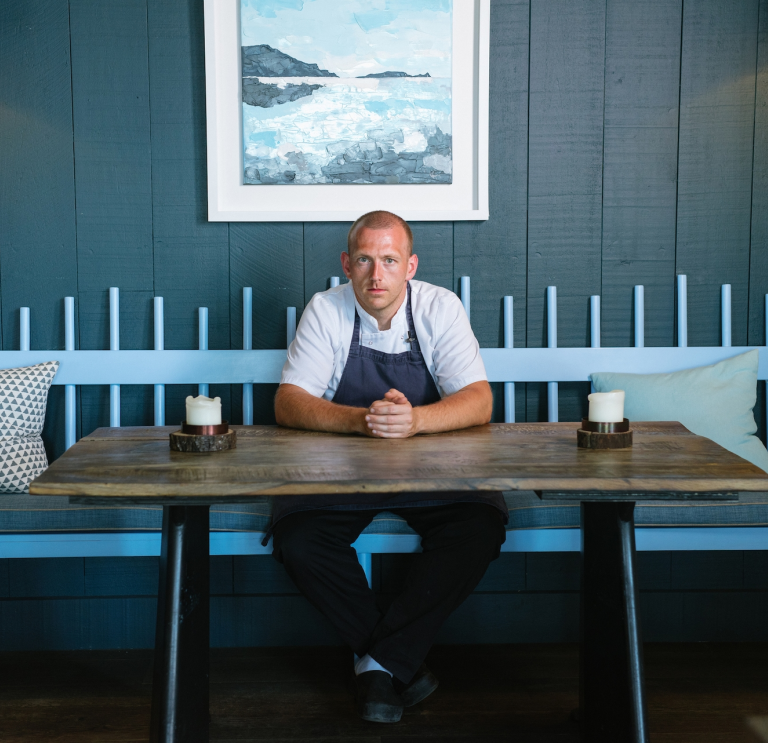 Hywel Griffith sentado en una mesa en su restaurante Beach House.
