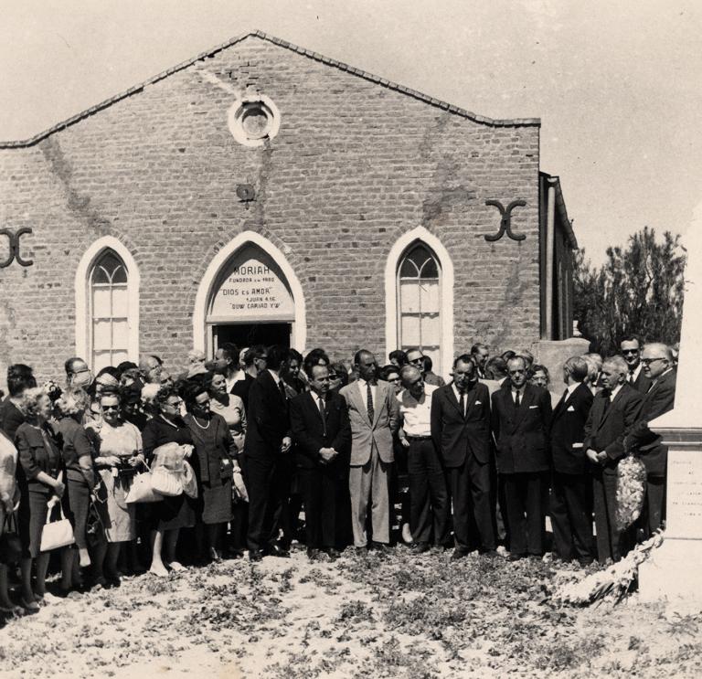 « Groupe de quatre personnes debout devant un mémorial, la chapelle Moriah ».