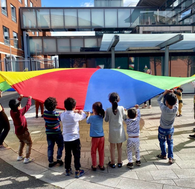 Un grupo de niños jugando con un paracaídas.