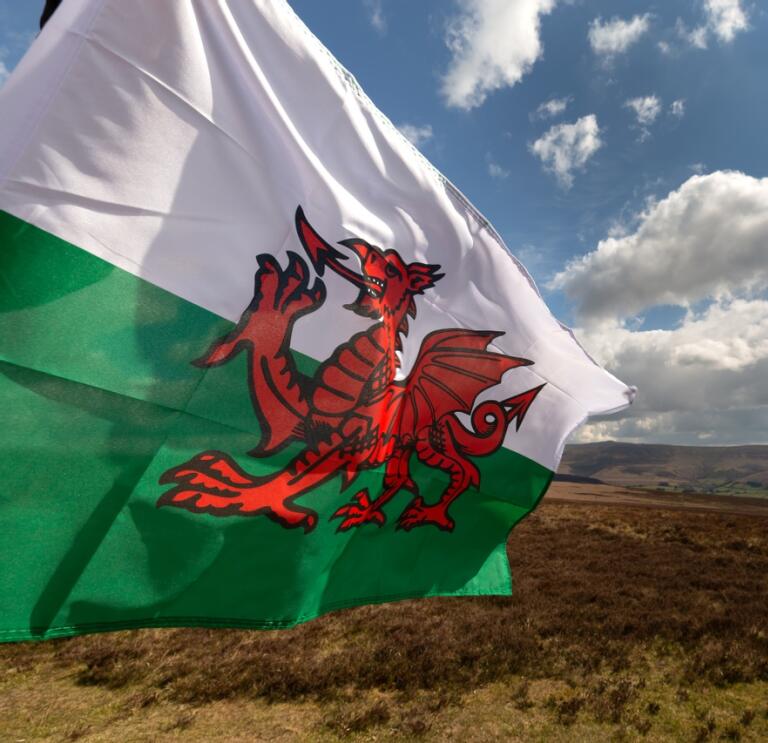 A Welsh flag blowing in the wind across a beautiful mountainous moorland scene 