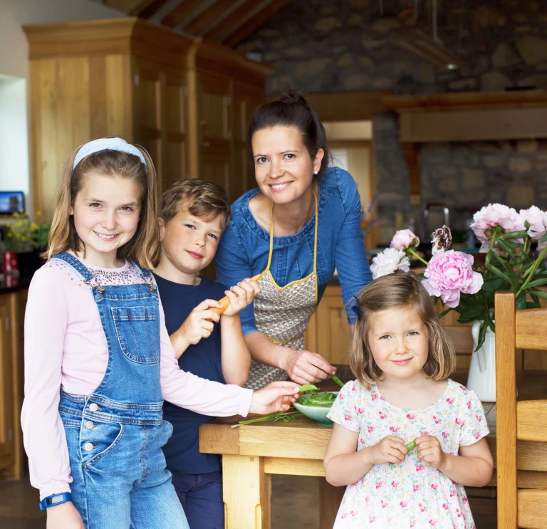 Una mujer en su cocina rodeada de sus tres hijos pequeños