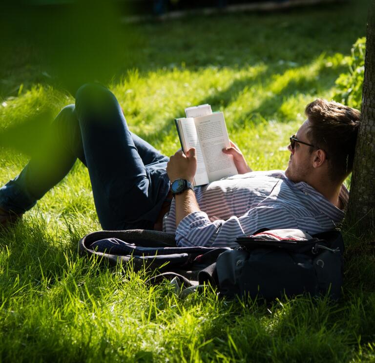 A person lying on the grass reading a book.