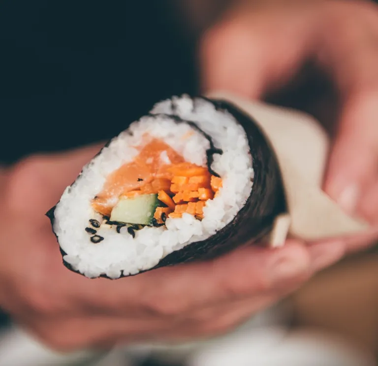 Una mano sosteniendo un rollo de sushi.