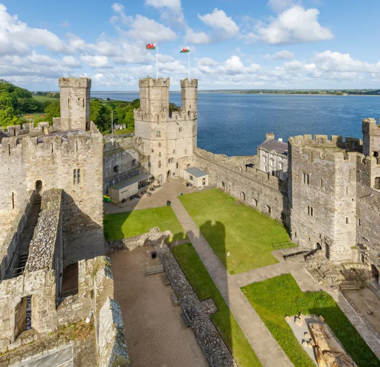 Una imagen del castillo de Caernarfon, mostrando el césped interior del castillo con el mar de fondo.