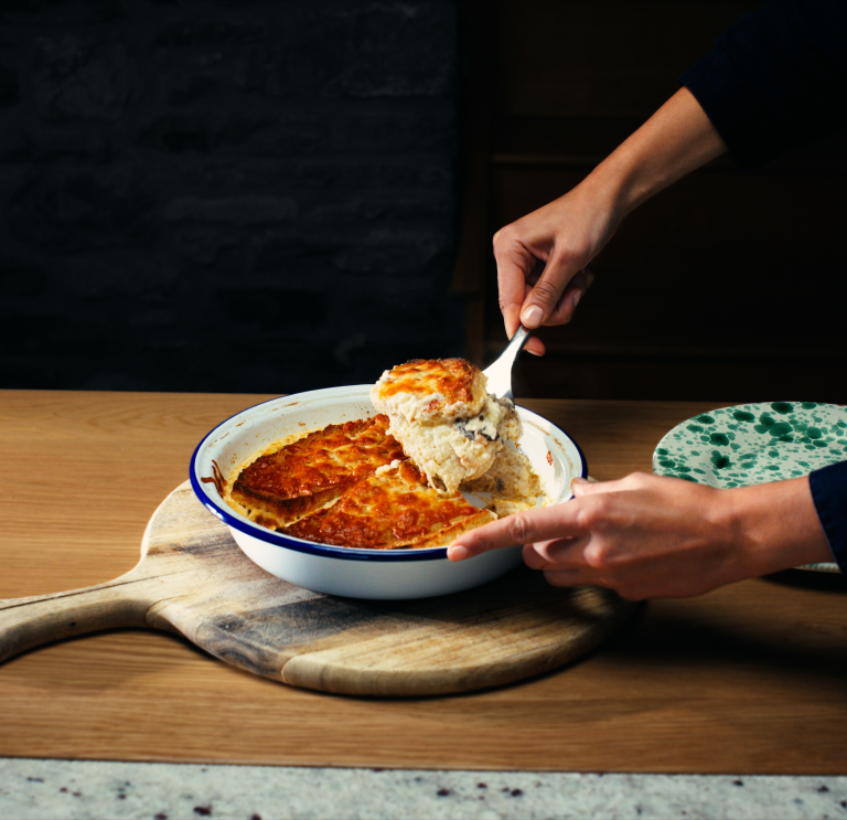 Ein Tablett mit walisischem Käsepudding, wobei die Hand eines Kochs eine Portion auf eine Scheibe Brot schöpft.