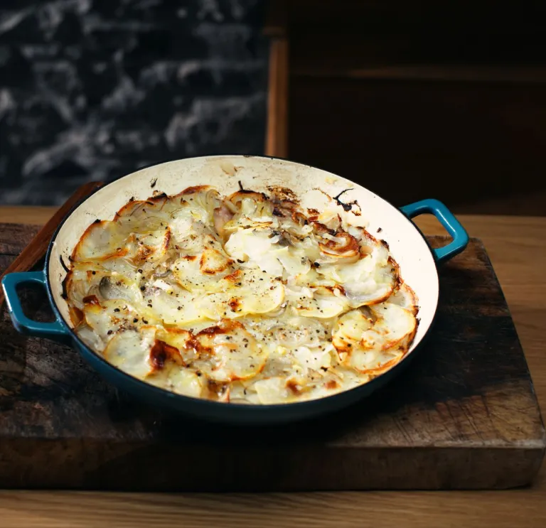 Una sartén de hierro fundido bellamente presentada con un pastel de cebolla galés recién hecho.