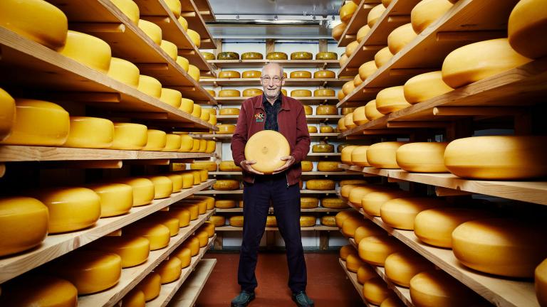 John Savage-Onstwedder amongst shelves of cheese
