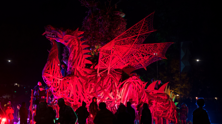 Toma nocturna de la escultura gigante del dragón rojo con gente parada mirando