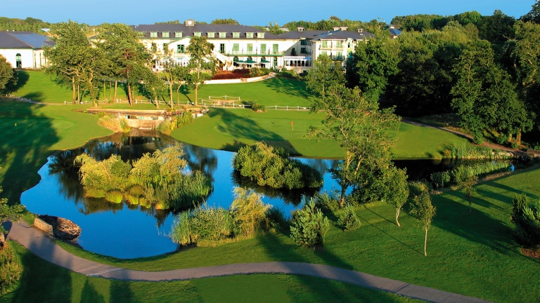 A hotel with a beautiful lake and grounds in front.