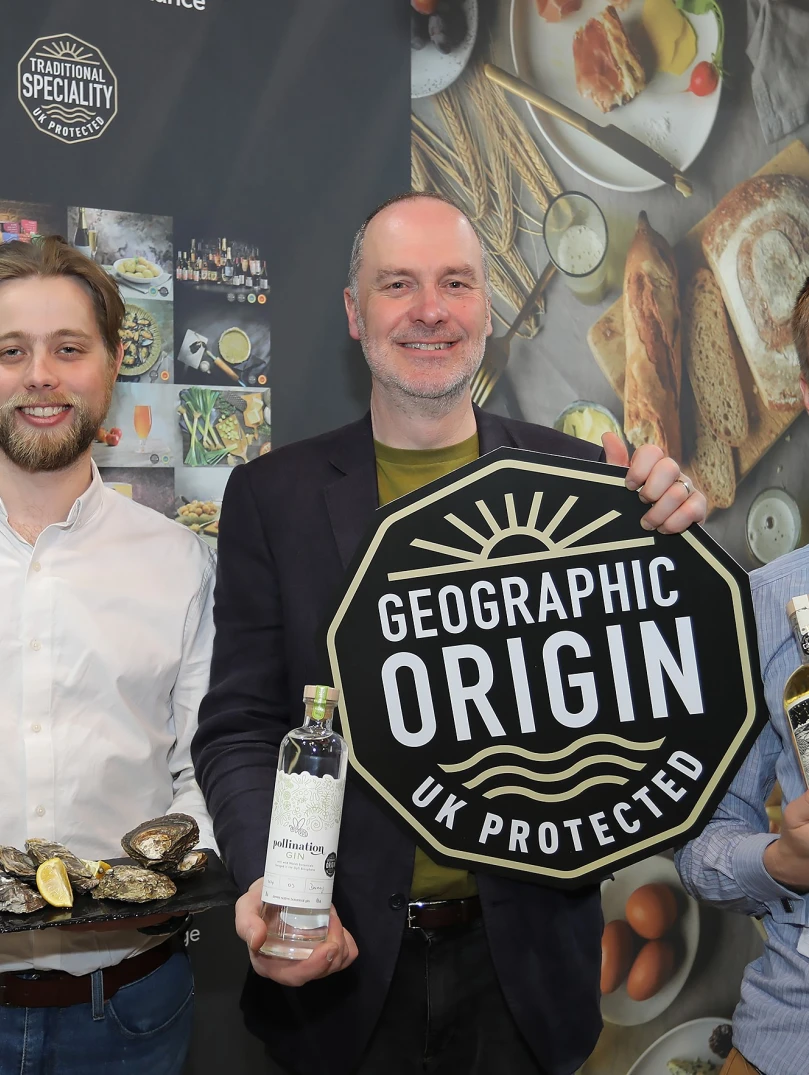 Three men holding their products smiling at the camera.