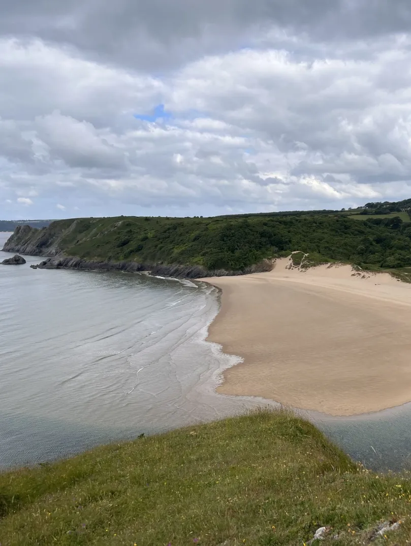 A scenic shot of a beautiful sandy bay with green mountains lining the sea