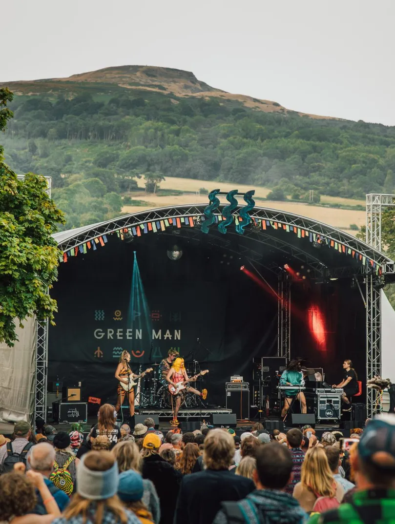 A band performing at the Green Man Festival with a crowd looking on.