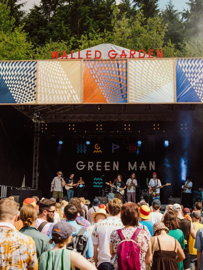 Musicians playing on a stage at the festival with a crowd of people.