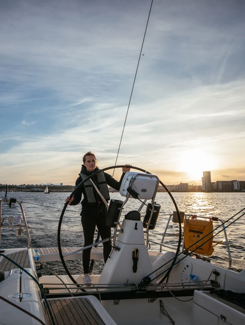 Hannah Mills al timón del yate, navegando en la Bahía de Cardiff