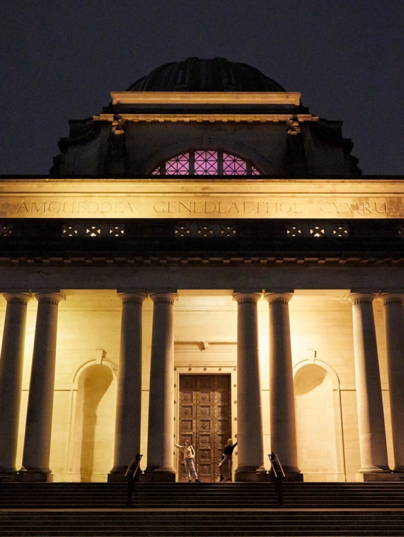 Vue extérieure de l'entrée d'un grand musée, éclairée la nuit.