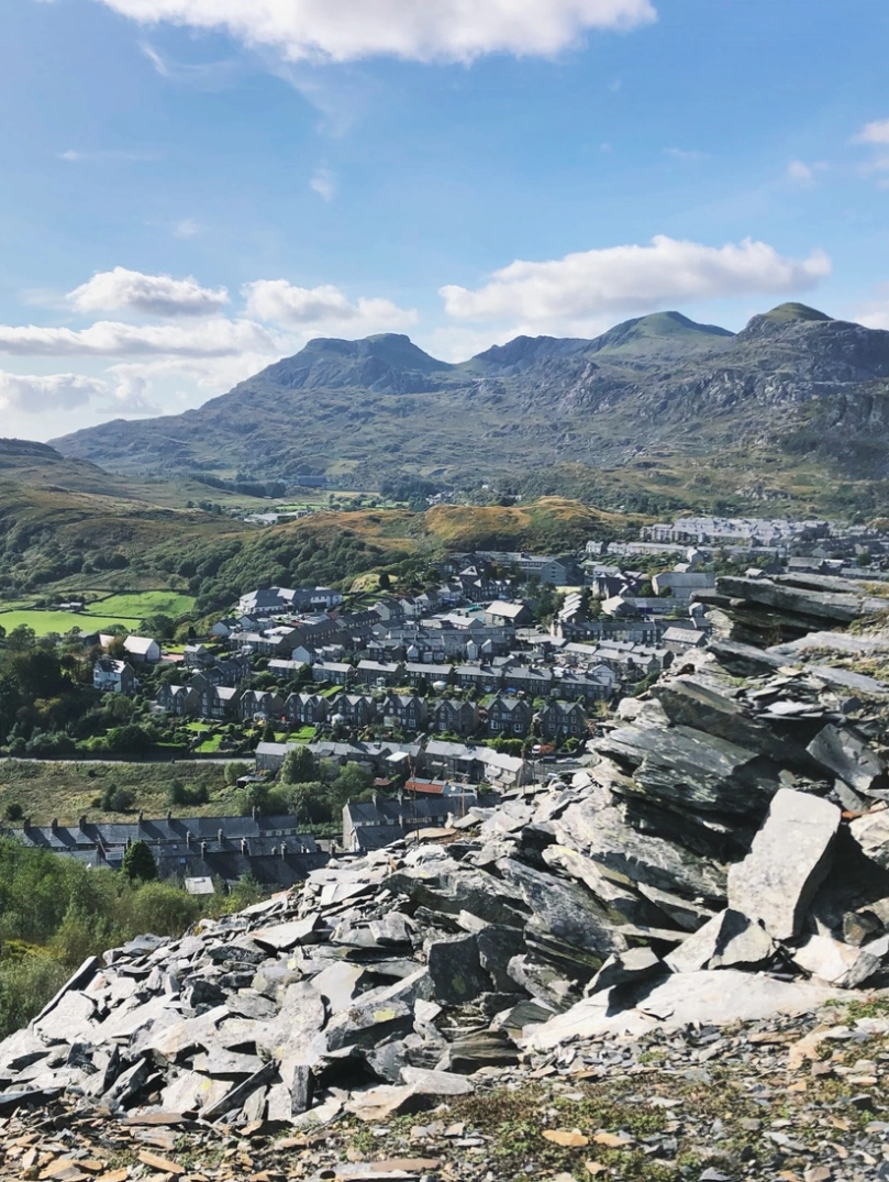 Une montagne d'ardoise au premier plan, avec des maisons en terrasse et d'autres montagnes en arrière-plan.