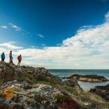 Four people walking along a craggy scenic coastline