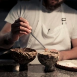 A chef preparing two bowls of food on a marble surface
