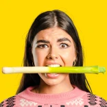 ピンクのジャンパーを着て、口にリーキをくわえた女性