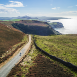 A road through the mountains with the sea in background.