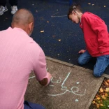 A man and his son drawing in chalk on the pavement