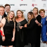 A group of people smiling and holding their award.