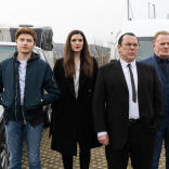 A group of actors standing in front of a car