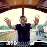 A man DJing at the back of a train.